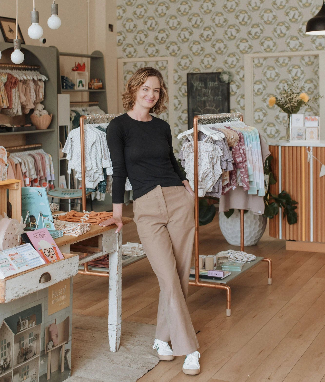 Maris, owner of Broomtail Kids, standing in front of a rack of ehtically sourced children's clothing