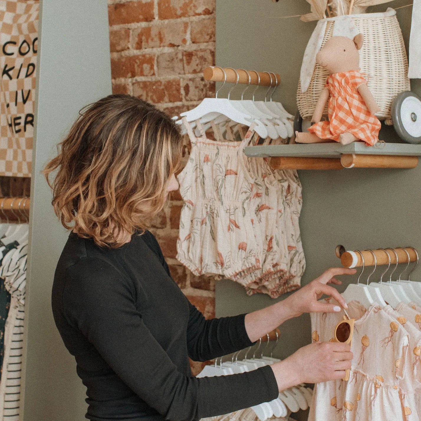 Founder of mom-owned boutique, Broomtail, arranging a rac kof ethically sourced children's clothing