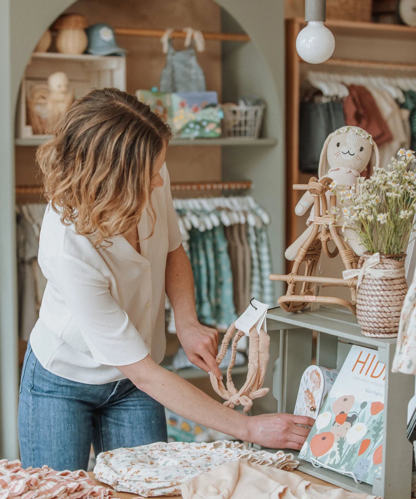 Kids boutique owner organizing items at a table assortment of ethically sourced children's clothing